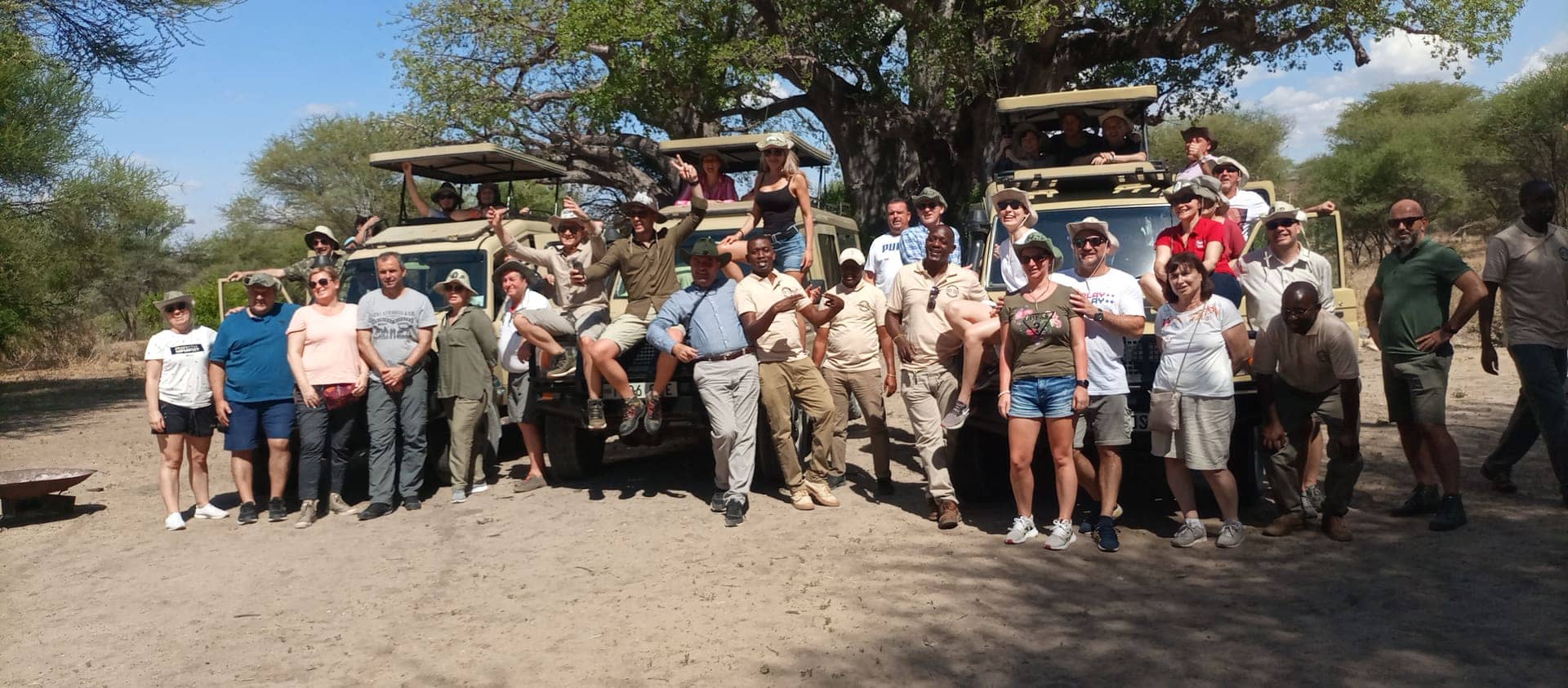 Guests and guides gathered with the vehicles under a baobab