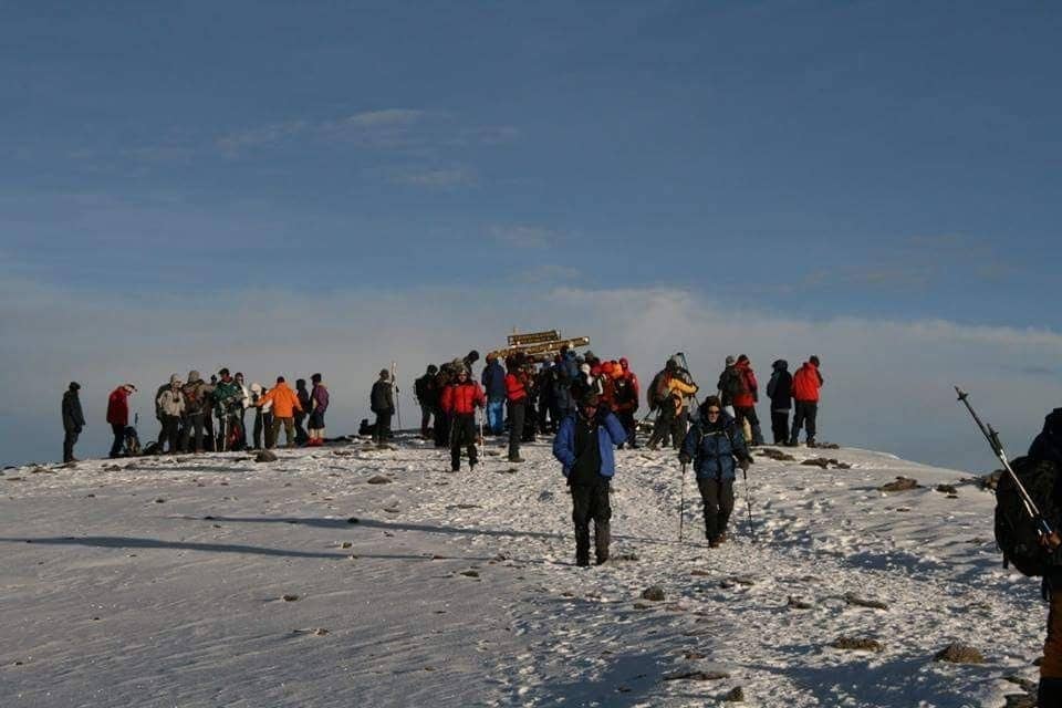 Climbers gathered at Uhuru Peak on the snowy roof of Kilimanjaro