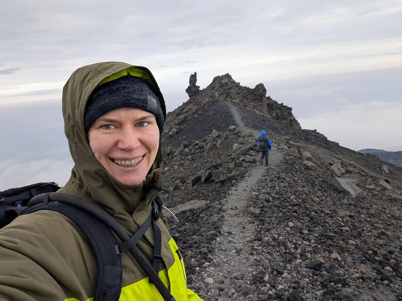 A smiling guest on the Mount Meru summit ridge above the clouds