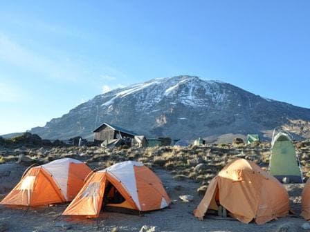 Orange tents at camp with the summit of Kibo behind