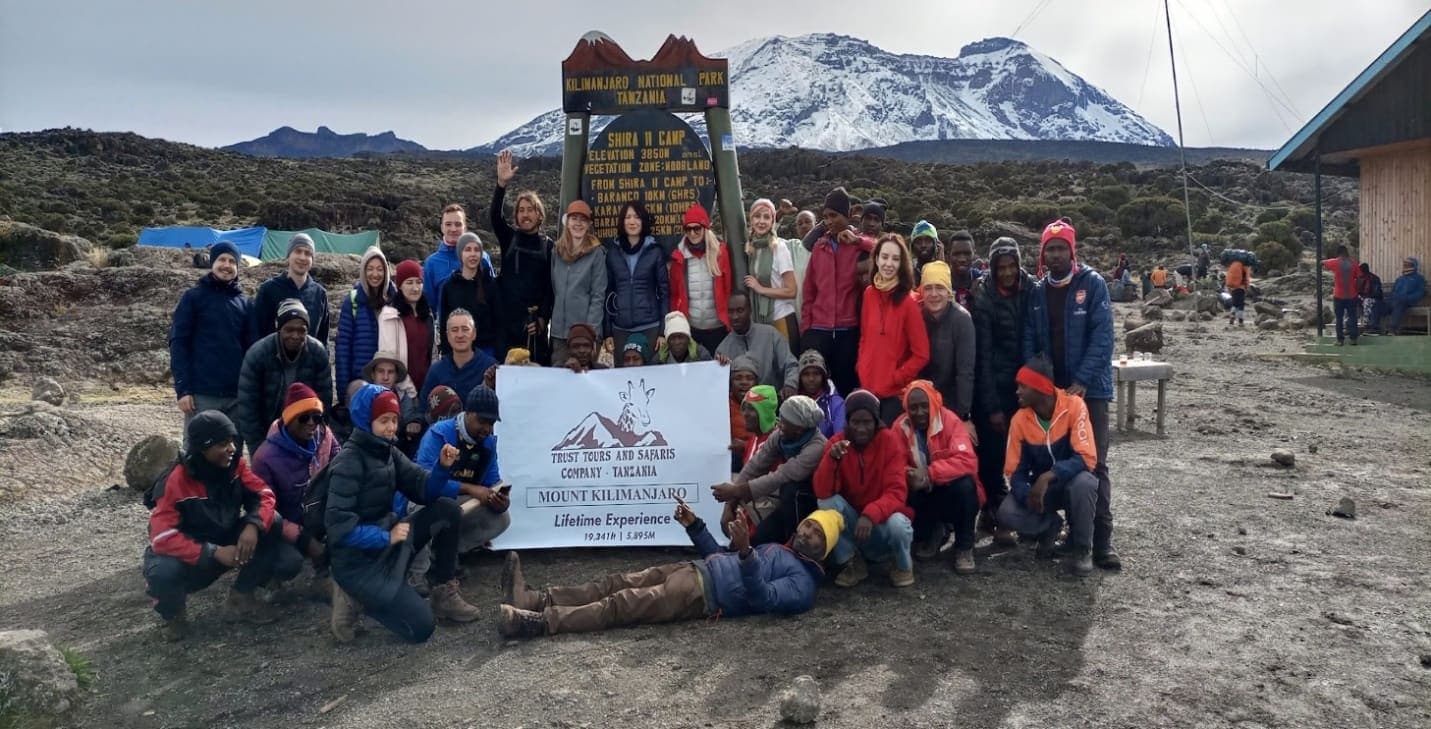 A Trust Tours & Safaris climbing team and crew with the company banner on Kilimanjaro
